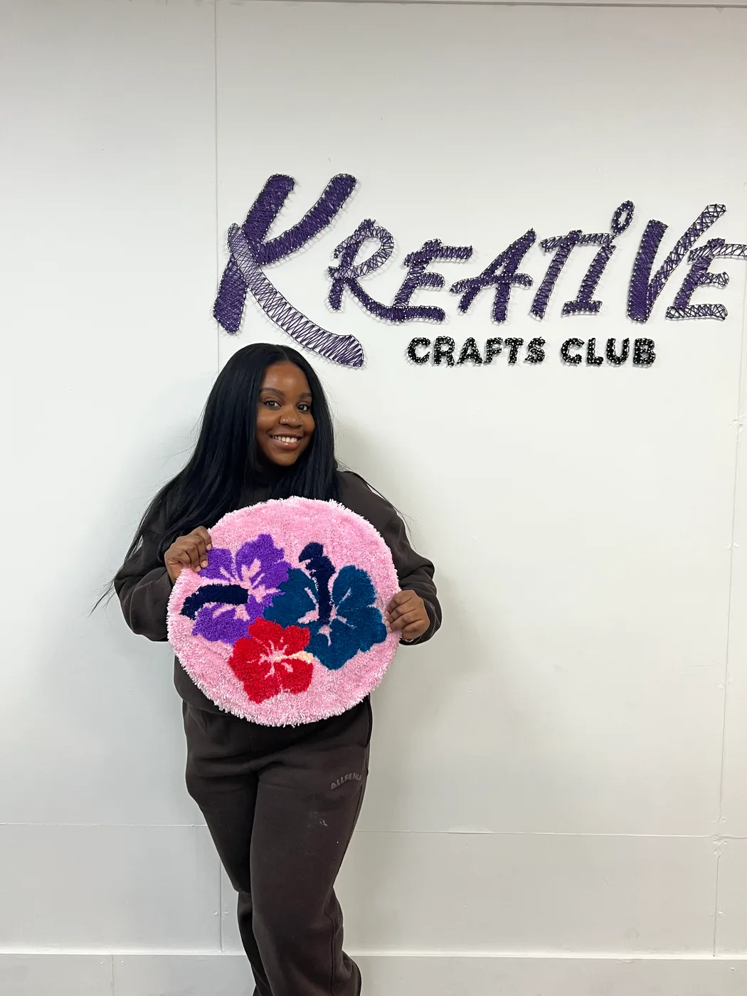 Janita holding a pink tufted rug at Kreative Crafts Club